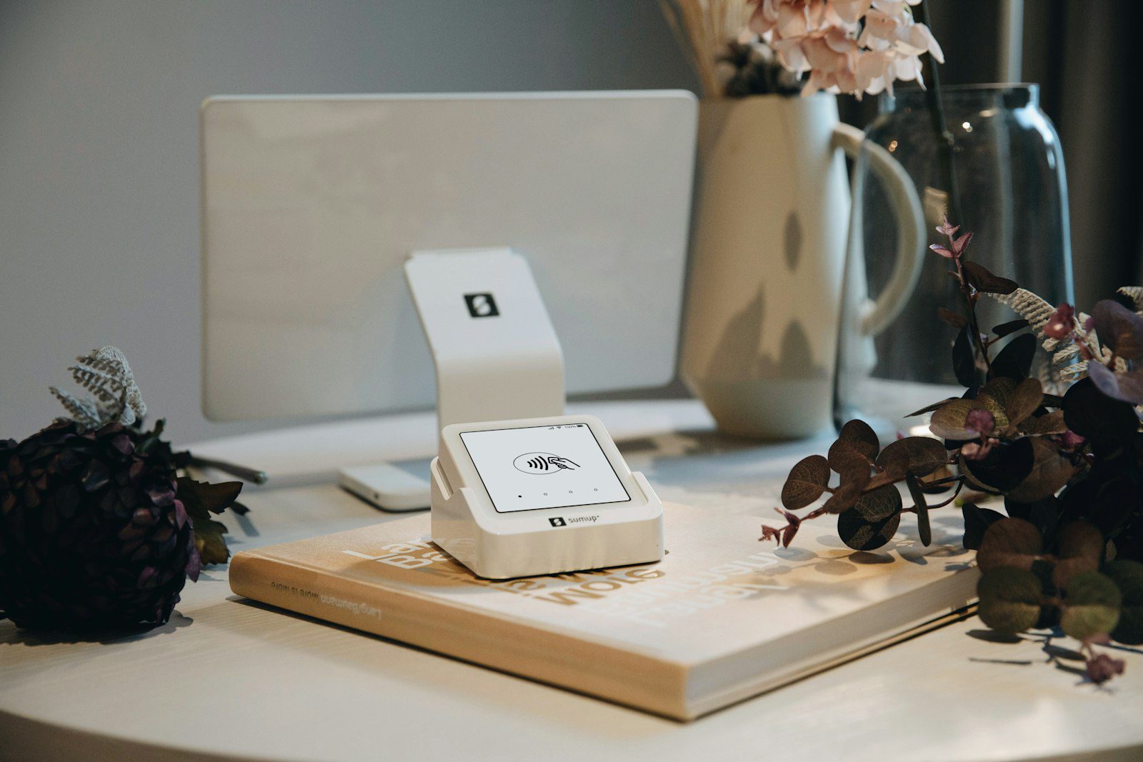 Card reader and till screen on a shop counter beside a vase of flowers