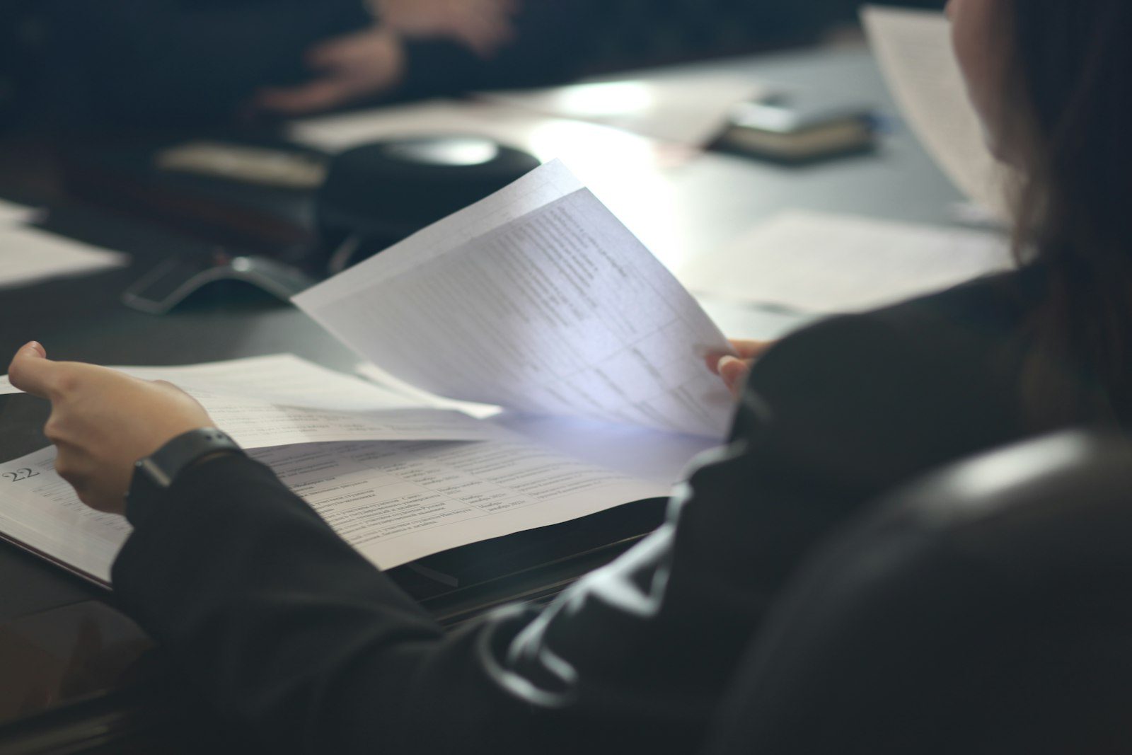 Woman sitting at a table reading through a printed page before it goes out