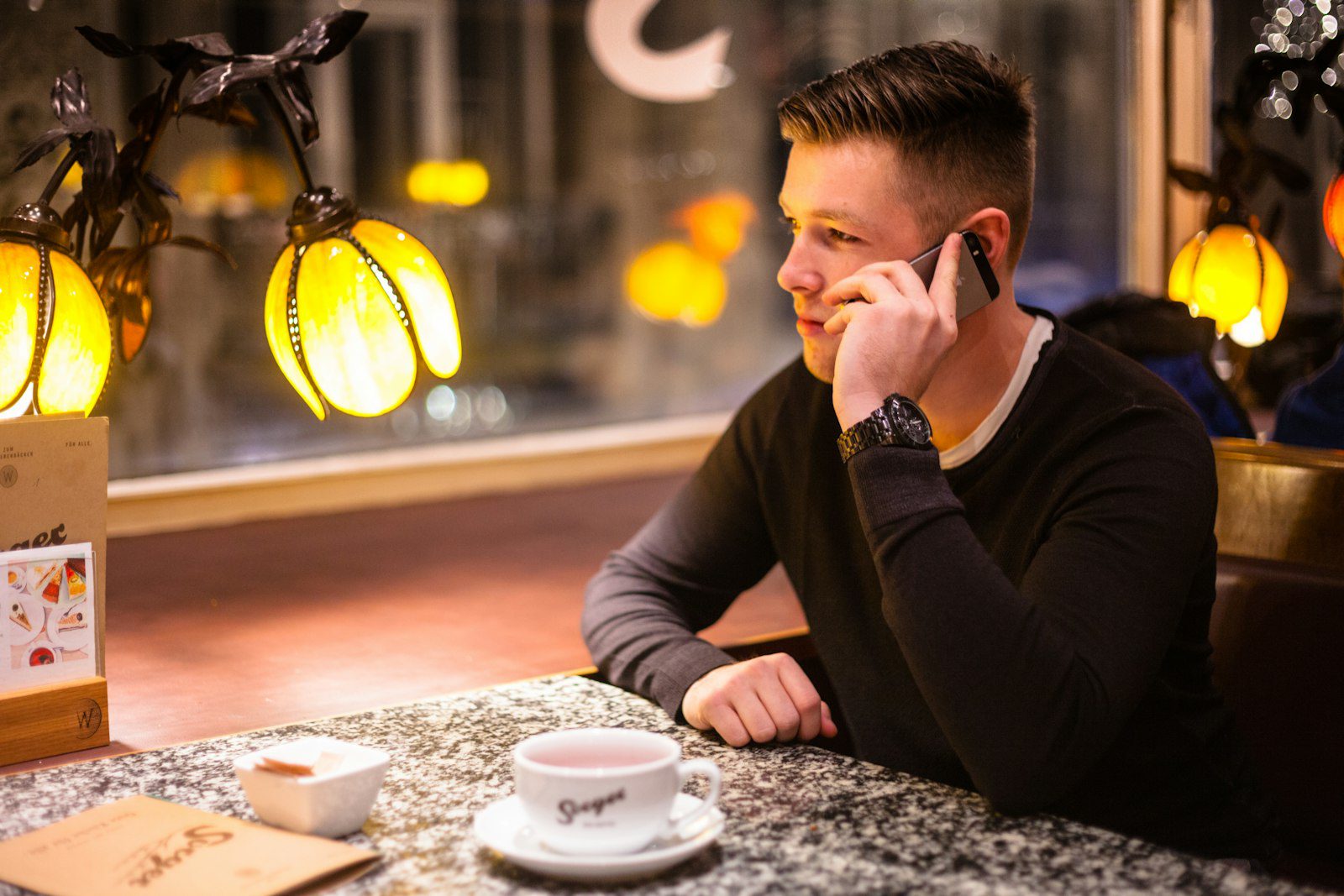 Business owner at a cafe table checking customer messages on his phone