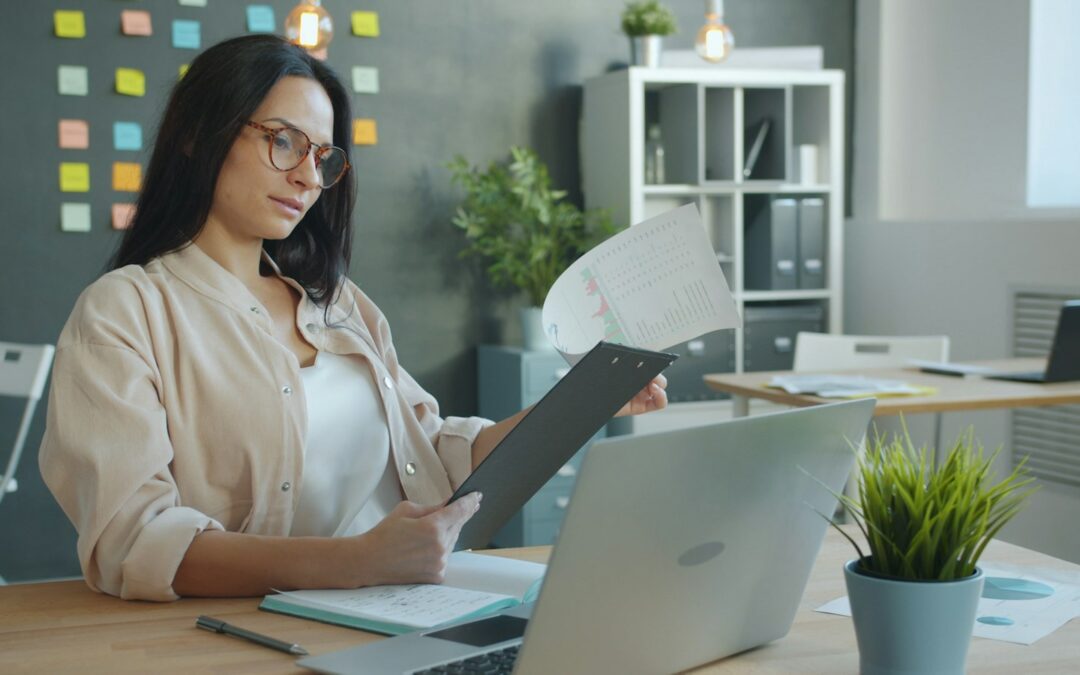 Business owner checking a client document against her laptop before using AI
