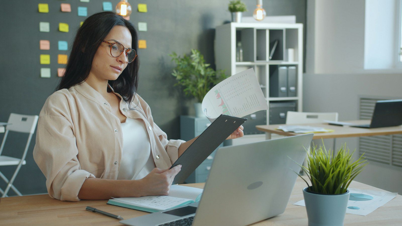 Business owner checking a client document against her laptop before using AI